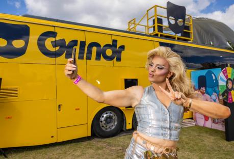 Person taking a selfie in front of a Grindr bus.