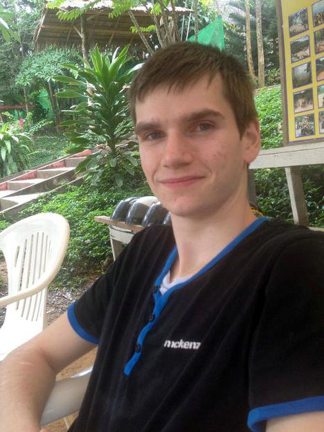 Daniel Whitworth, an alleged victim of Stephen Port, smiling in a black and blue shirt with a tropical background.