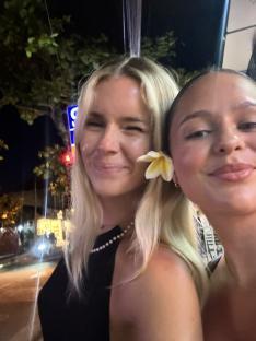 Two women smiling for a selfie at night.