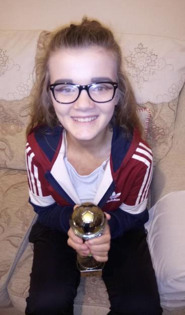 Teenage girl holding a soccer trophy.