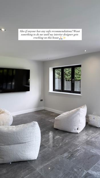 Interior of a room with white beanbag chairs, a large TV, and dark gray floor tiles.