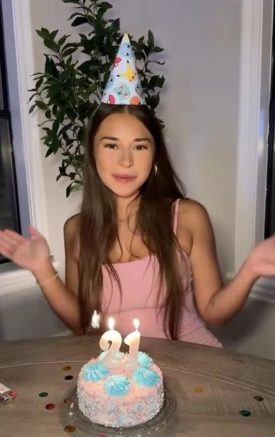 Sophie Rain celebrating her 21st birthday with a cake and wearing a party hat.