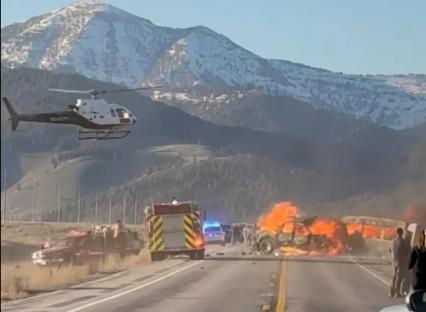 Rescue workers and a helicopter at the scene of a fiery vehicle collision.