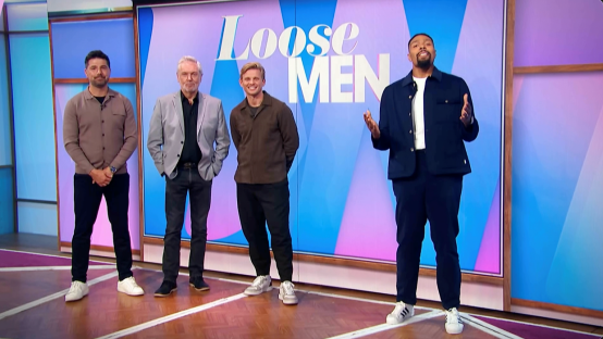 four men stand in front of a loose men sign