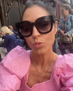 Woman in pink puff-sleeve top and sunglasses making a kissy face.