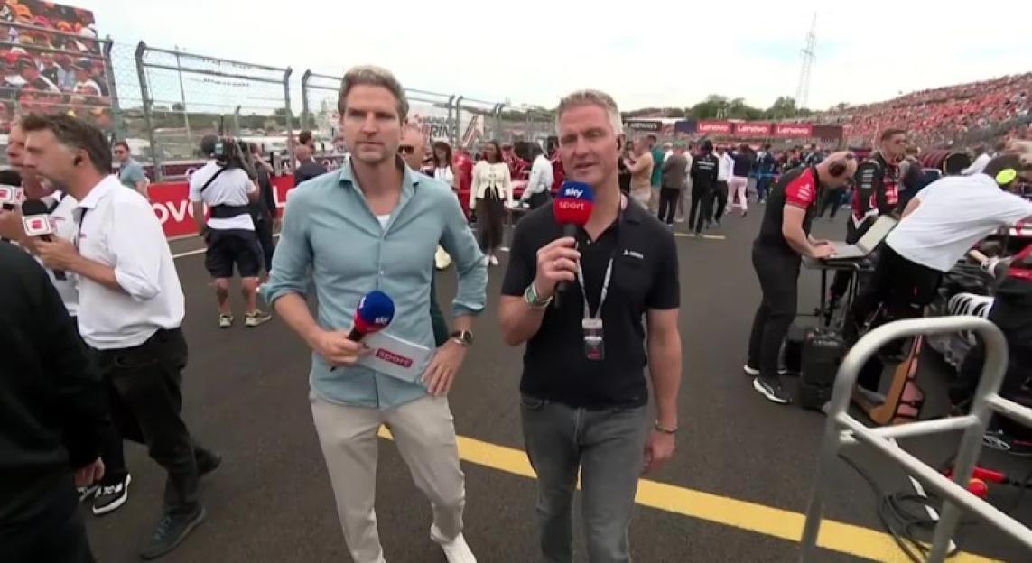 Peter Hardenacke and Ralf Schumacher conducting an interview at a racetrack.