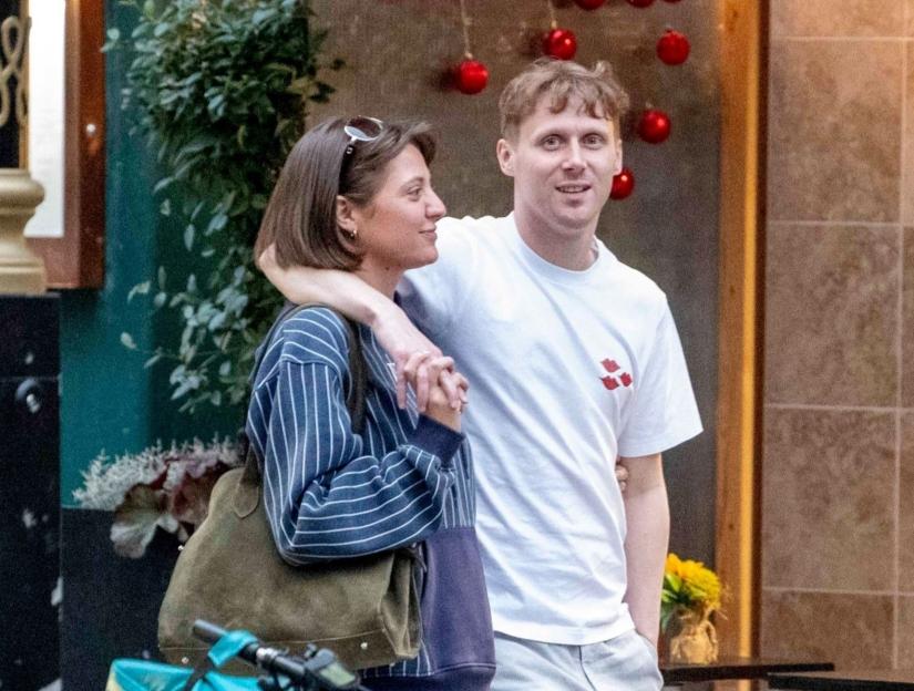 Jamie Borthwick and Georgina Shave embracing each other on a street with a bicycle in the foreground.