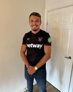Man smiling while wearing a West Ham United jersey.