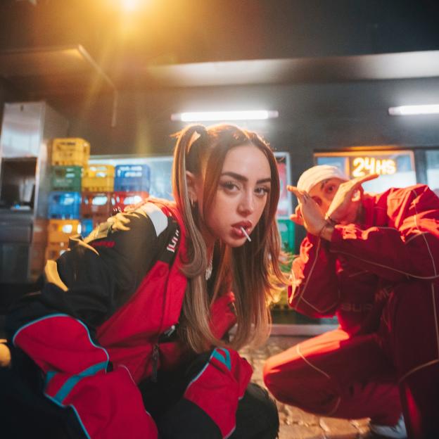 Photo of two people in red clothing; one person is sucking on a lollipop.