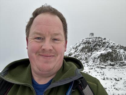 Selfie of a man smiling on a snow-covered mountain.