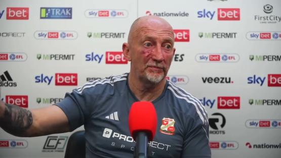 Man with a facial injury speaks into a microphone.