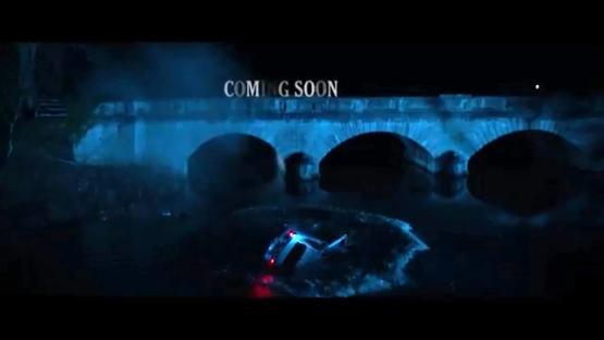 A car submerged in a river under a bridge at night;