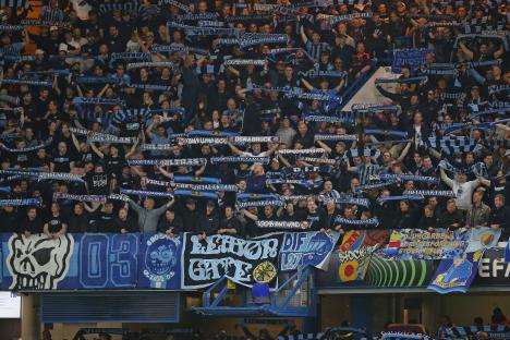 Djurgården supporters holding scarves at a soccer match.
