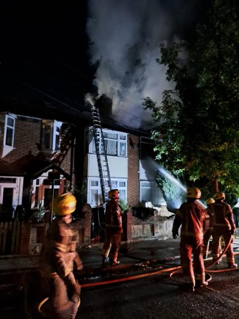 Firefighters extinguishing a house fire at night.