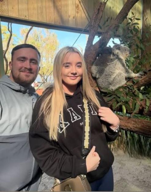 Couple posing with a koala at a zoo.