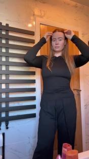Woman in black long-sleeved shirt and pants in a bathroom.