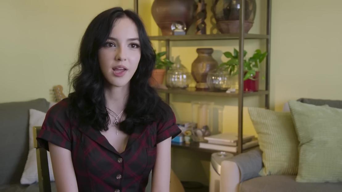 Woman with dark hair speaking to camera.