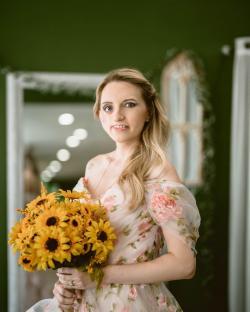 Woman in floral dress holding a bouquet of sunflowers.