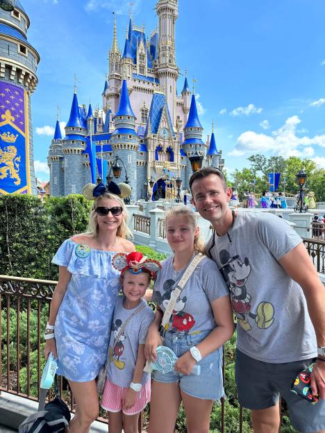 A family of four stands in front of Cinderella Castle at Disney World.