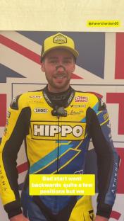 Racer in yellow and blue racing suit reporting on a race.