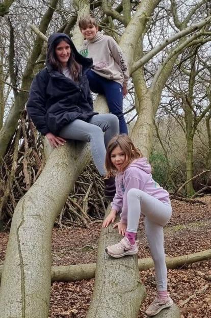Family sitting on fallen tree trunks in a forest.
