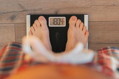 Man weighing himself on a digital scale.