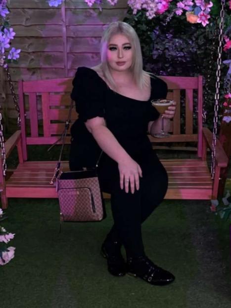 Megan Evanson sitting on a swing with a drink.