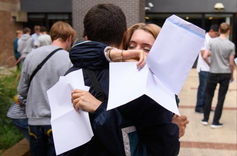 Students embrace after receiving GCSE exam results.