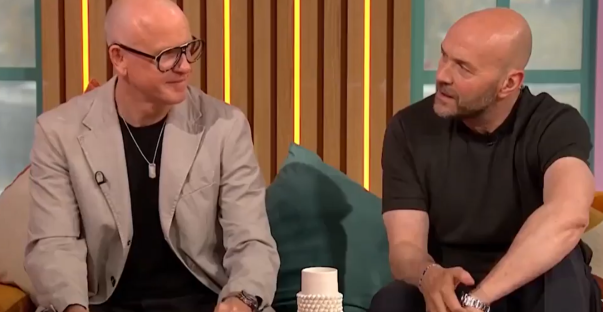 Two bald men sitting and talking on a talk show.