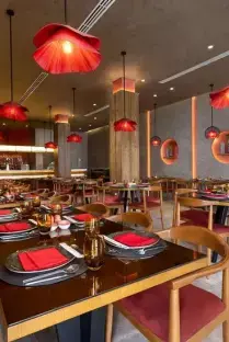 Restaurant interior with red pendant lights and tables set for dining.