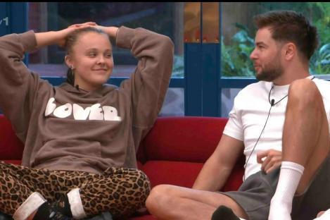 JoJo Siwa and Chris Hughes on a red couch.
