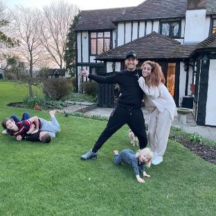 Family playing on the lawn in front of their house.
