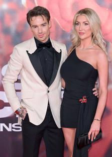 a man in a tuxedo and a woman in a black dress pose for a photo