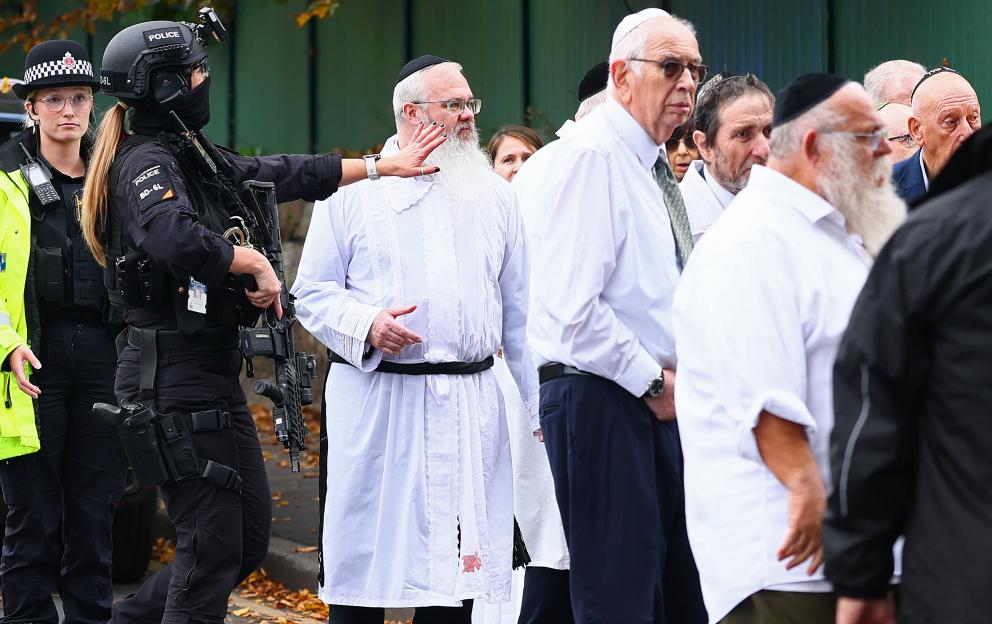 Rabbi Daniel Walker stands among armed police officers and members of the Jewish community outside Heaton Park Hebrew Congregation synagogue following an attack.