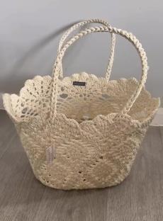 Cream-colored crocheted tote bag with braided handles.