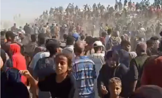 Large crowd of people gathered, many on horseback or camels in the background.
