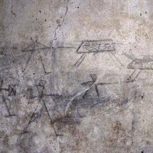 Ancient children's drawings of gladiators on a wall in Pompeii.