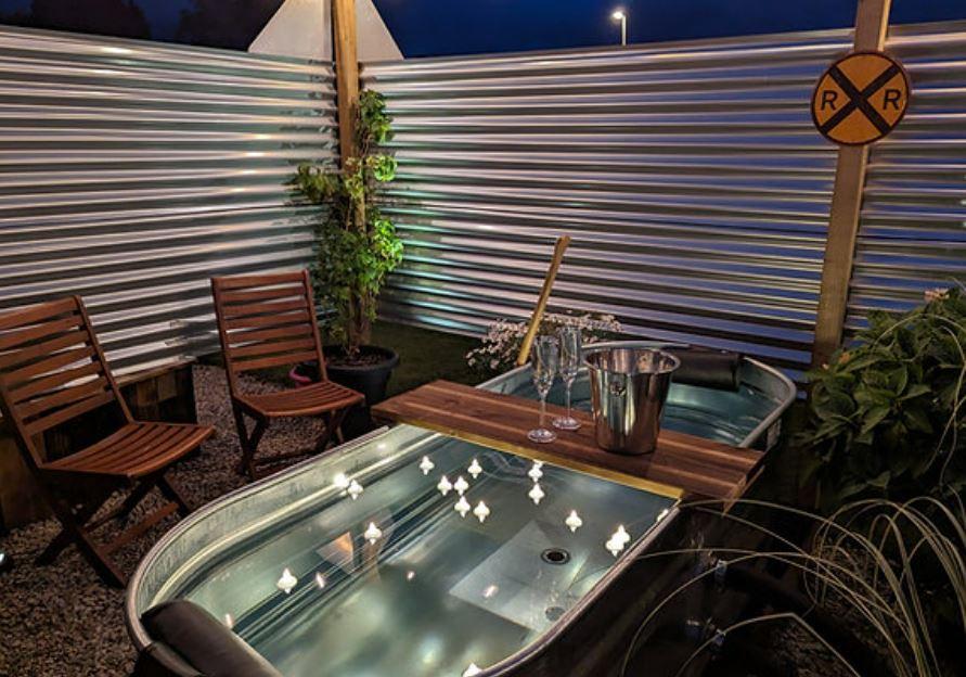 Romantic outdoor soaking tub with candles and champagne.