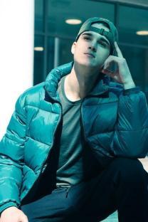 Portrait of a young man in a teal puffer jacket.