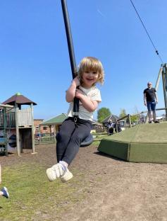 Smiling toddler on playground zipline.