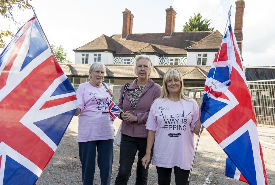 Three women holding Union Jack flags and wearing pink t-shirts with a slogan.