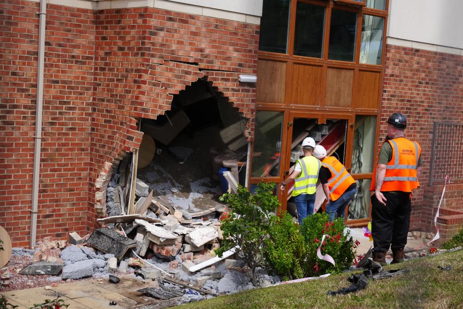 The aftermath of a car crashing into Highcliffe Care Home in Sunderland, with a large hole in the brick wall and debris scattered.