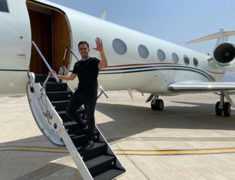 Simon Leviev waving as he exits a private jet.