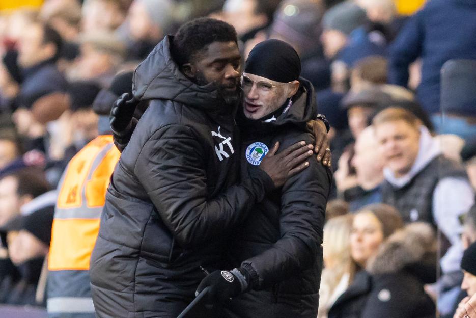 Kolo Toure and Ashvir Singh Johal hugging after a Wigan Athletic soccer game.