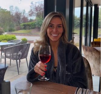 Woman in a robe enjoying wine at a restaurant.