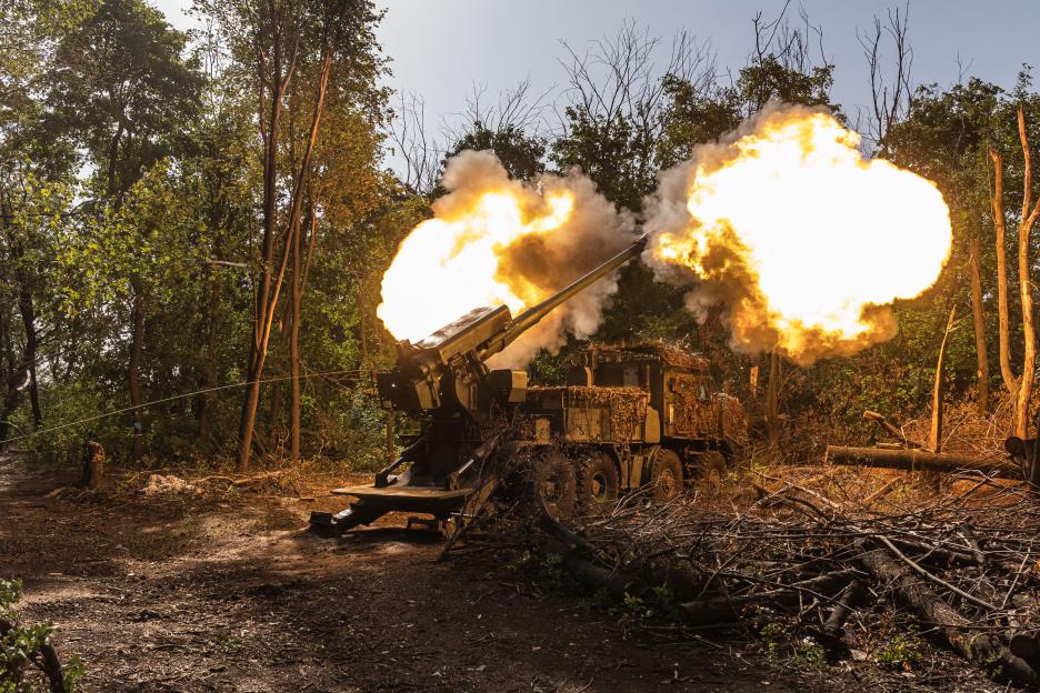 Ukrainian soldiers firing artillery in a wooded area.
