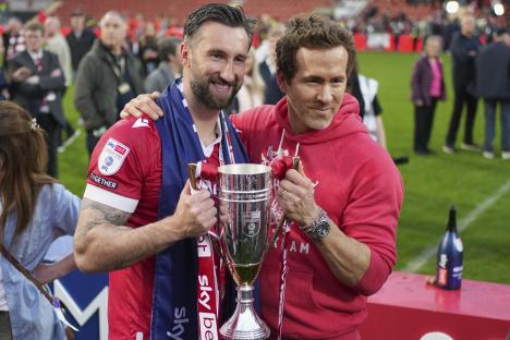 Ryan Reynolds and a Wrexham player holding a trophy.