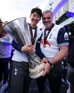 Son Heung-min and Tottenham Hotspur head coach Ange Postecoglou holding the UEFA Europa League trophy.