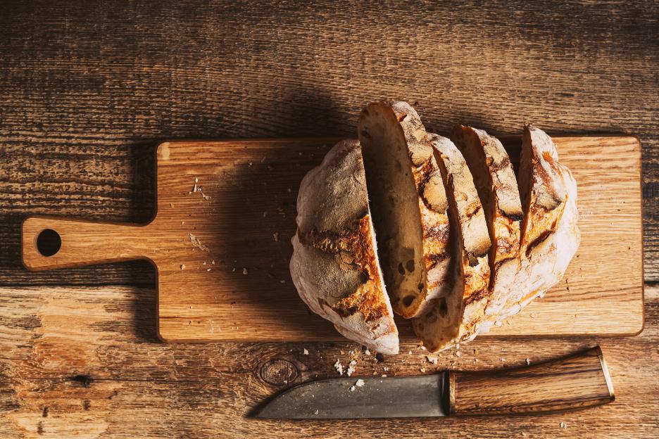 Sliced artisan bread on a cutting board with a knife.