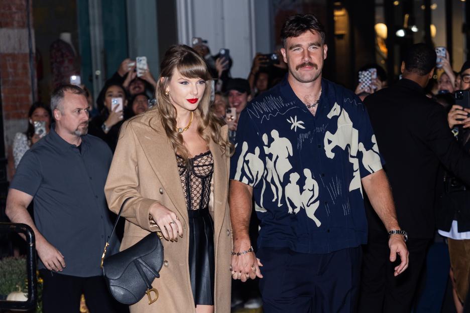 Taylor Swift and Travis Kelce holding hands.